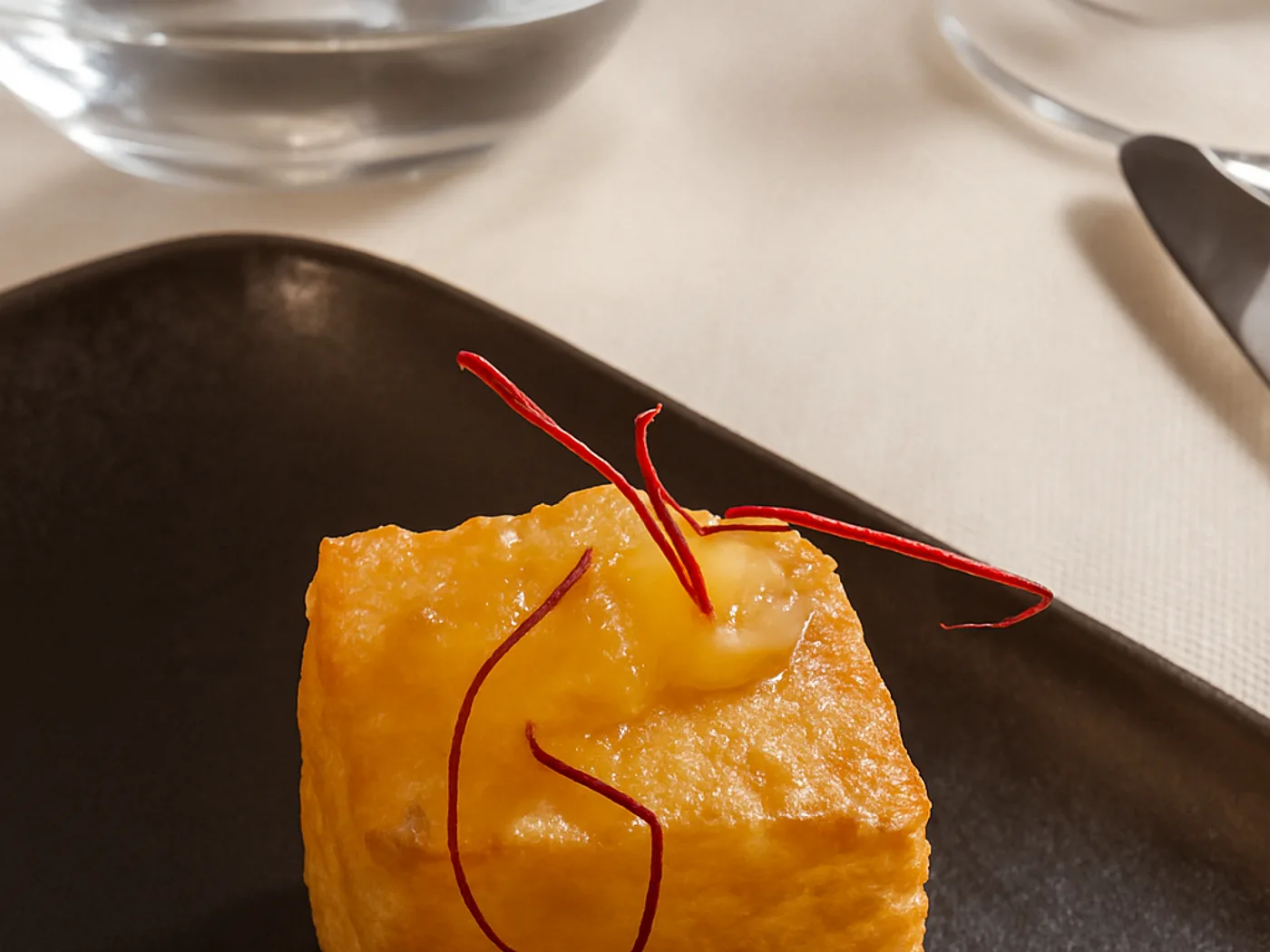 Tortino allo zafferano con fili rossi su piatto scuro